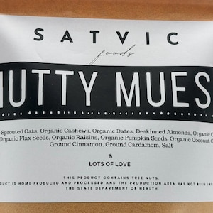 May include: A white label with the words "SATVIC foods" and "NUTTY MUESLI" in bold black letters. The label lists ingredients like organic oats, cashews, dates, and chia seeds. The text "LOTS OF LOVE" is also included.