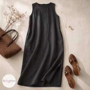 May include: A sleeveless, charcoal-colored linen dress with a round neckline and side slits. The dress is paired with brown leather sandals, a woven tote bag, and delicate gold jewelry. A sprig of dried flowers adds a natural touch.