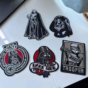 Puede incluir: Conjunto de seis parches bordados con temática de Star Wars. Los diseños incluyen a Darth Vader en varias poses, un Stormtrooper y logotipos de Star Wars. Los parches son de color negro, blanco, rojo y gris.