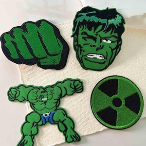 Può includere: Set di quattro toppe ricamate con Hulk. Include un pugno verde, una faccia verde, una figura a corpo intero di Hulk con pantaloncini blu e un simbolo di radiazione verde e nero. Le toppe sono bordate di nero.