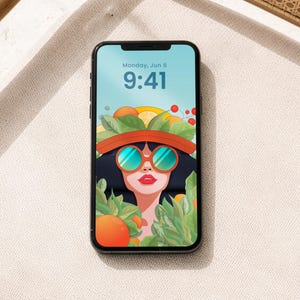 May include: A black smartphone displays a colorful illustration of a woman wearing sunglasses and a hat adorned with fruit and leaves. The screen shows the date and time: Monday, Jun 6, 9:41.