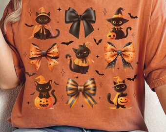 Puede incluir: Una camiseta de color naranja quemado con un patrón repetitivo de gatos negros con sombreros de bruja, lazos a rayas naranjas y negras, y calabazas. El gráfico incluye pequeños murciélagos negros y estrellas dispersas.