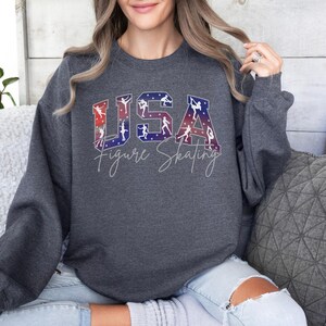 Dark heather gray USA Figure Skating sweatshirt with patriotic varsity lettering and skater silhouettes, cozy skating mom crewneck, winter sports fan sweatshirt, ice skating lover gift.