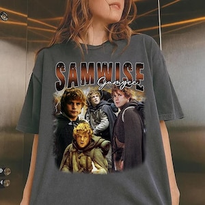 Op de afbeelding: Een antracietgrijs t-shirt met korte mouwen en een grafische print van Samwise Gamgee uit The Lord of the Rings. Het ontwerp bevat de tekst "SAMWISE" in een vet, verweerd lettertype boven het personage en "Gamgee" in een cursief handschrift.