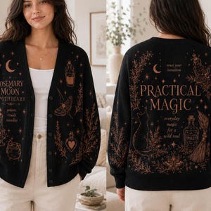 May include: A black button-down cardigan featuring copper-coloured graphic prints. The front displays the text Rosemary Moon Apothecary with illustrations of a candle, cauldron, and moth. The back features the text Practical Magic with a cat and broom.