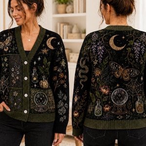 Può includere: Un cardigan nero con scollo a V, bordi e bottoni verde oliva scuro. La maglia presenta motivi dettagliati di una luna crescente, una falena, una ragnatela, una sfera di cristallo, boccette, serpenti e vari elementi floreali e botanici.
