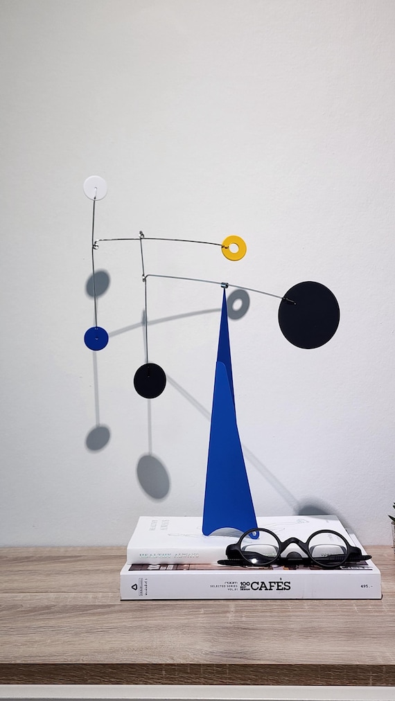 A handcrafted mid-century modern hanging mobile with blue geometric forms — the kind of slow, meditative kinetic art that makes a room feel intentional.