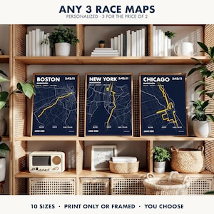 May include: Three vertical posters featuring dark blue maps of the Boston, New York, and Chicago marathons with yellow route lines. Each print displays the city name, marathon time, distance, elevation, and the name Jane Doe in white text.