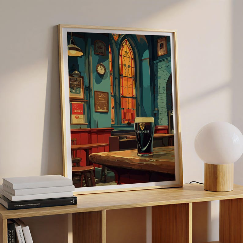 May include: Framed print of a pub interior with a pint of Guinness on a wooden table. The artwork features a dark, moody color palette with red, blue, and orange tones. The Guinness glass is centered, with the logo visible.