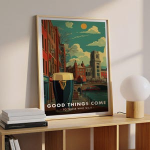May include: Framed art print featuring a pint of stout with a gold harp logo, set against a vintage-style cityscape with the text "GOOD THINGS COME - TO THOSE WHO WAIT." The artwork has a warm color palette.