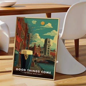 May include: A framed art print featuring a pint of stout in front of a cityscape with a bridge and buildings. The print has a gold frame and the text "GOOD THINGS COME TO THOSE WHO WAIT". The artwork has a vintage travel poster style.