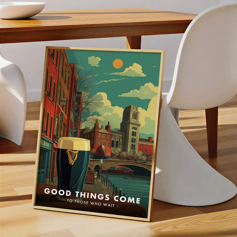 May include: A framed art print featuring a pint of stout in front of a cityscape with a bridge and buildings. The print has a gold frame and the text "GOOD THINGS COME TO THOSE WHO WAIT". The artwork has a vintage travel poster style.