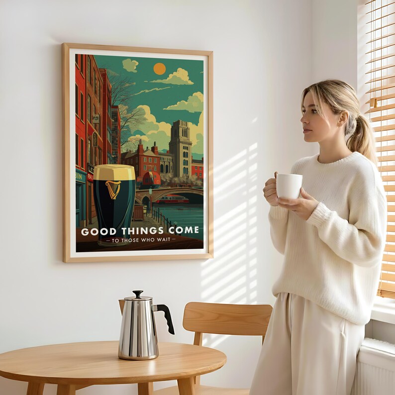 May include: A framed art print featuring a stylized illustration of a city scene with a large pint of stout. The artwork includes the text "GOOD THINGS COME - TO THOSE WHO WAIT". The print is in a light wood frame.