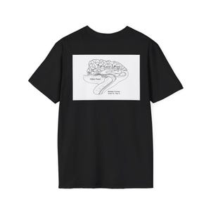 Può includere: T-shirt nero con una grafica bianca di una buca da golf. La grafica include il testo "Nikki Pond" e "Aman Corner Hole 12 - Par 3". La maglietta è realizzata in un materiale morbido.
