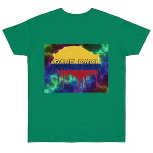 May include: A green t-shirt featuring a graphic design with the text "RAVE PAPI" in a stylized font. The design incorporates the colors of a flag, with yellow, blue, and red elements, and a dripping effect.