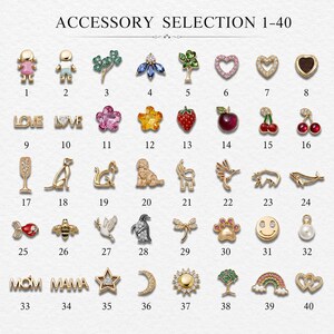 May include: A collection of forty small gold-toned metal charms labelled 1 through 40, featuring various shapes including figures, animals, fruits, flowers, celestial bodies, and text like LOVE, MOM, and MAMA, accented with colourful enamel and crystals.