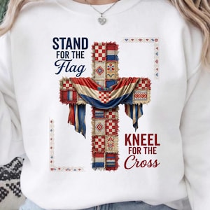 Può includere: Felpa bianca con un design a croce che incorpora la bandiera croata. La croce è composta da quadrati patchwork rossi, bianchi e blu. Il testo sulla maglietta recita "STAND FOR THE FLAG" e "KNEEL FOR THE CROSS."