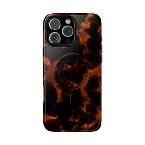 Puede incluir: Una funda para smartphone con un patrón de carey en tonos marrón oscuro y ámbar con acabado brillante. La funda incluye un anillo de carga magnético circular en la parte posterior y un recorte para una cámara de triple lente en la esquina superior.