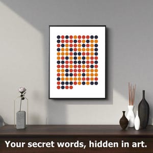 Op de afbeelding: Een ingelijste kunstafdruk met een patroon van rode, oranje en marineblauwe stippen. Het kunstwerk wordt gepresenteerd op een witte achtergrond en bevat de tekst "Your secret words, hidden in art."
