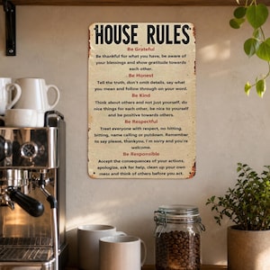 May include: A rectangular metal wall sign with a distressed cream background and black text reading HOUSE RULES. It lists five principles: Be Grateful, Be Honest, Be Kind, Be Respectful, and Be Responsible, each followed by descriptive text in black.