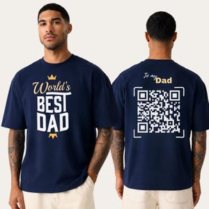 May include: A navy blue short-sleeved t-shirt featuring the text World's BEST DAD in white and gold on the front. The back displays the text To my Dad in gold above a large white QR code graphic on a navy blue background.