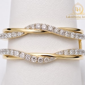 Puede incluir: Un protector de anillo dorado con un diseño en espiral, incrustado con pequeños diamantes brillantes. El protector de anillo está diseñado para realzar el aspecto de un anillo solitario. El texto "LakshHriday Jewels" es visible.