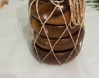 Puede incluir: Un conjunto de cuatro posavasos de madera marrón oscuro, atados con hilo natural. Los posavasos están diseñados para proteger las superficies de las marcas de bebidas. Cada posavasos tiene un diámetro de aproximadamente 10 cm.