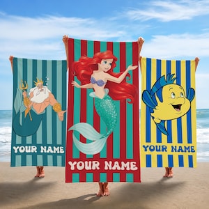 May include: Three beach towels featuring characters from The Little Mermaid. One shows King Triton, another Ariel, and the third Flounder. Each towel has vertical stripes and the text "YOUR NAME" at the bottom.