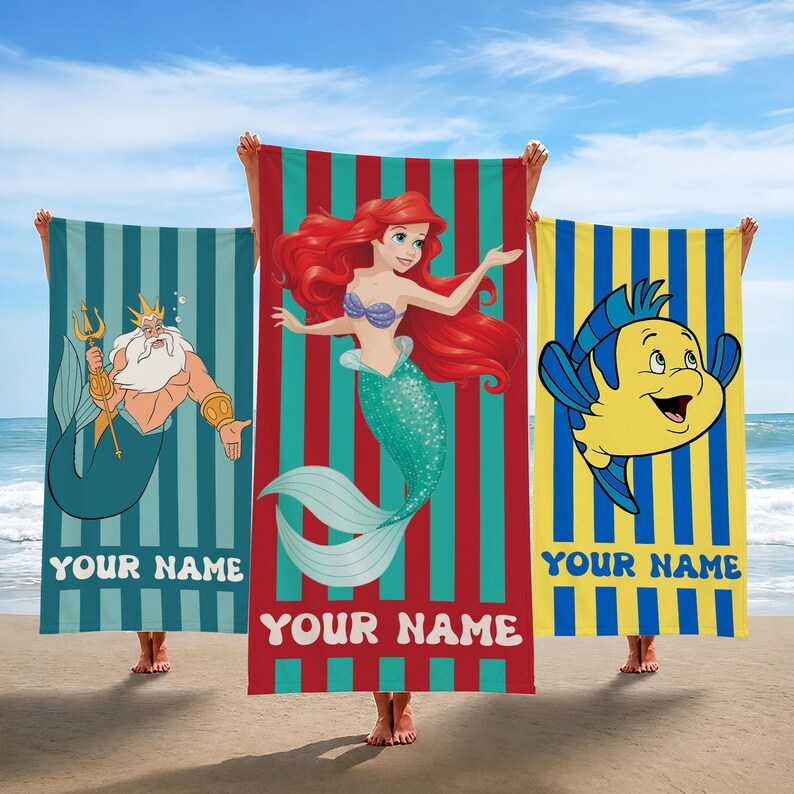 May include: Three beach towels featuring characters from The Little Mermaid. One shows King Triton, another Ariel, and the third Flounder. Each towel has vertical stripes and the text "YOUR NAME" at the bottom.
