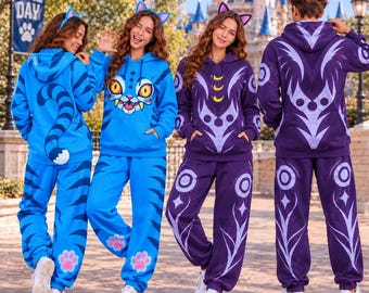 May include: Four individuals wearing matching hooded sweatshirts and sweatpants sets. Two sets are bright blue with cat-ear headbands, featuring a cartoon cat face, tail, and paw prints. Two sets are deep purple with moon and geometric patterns.