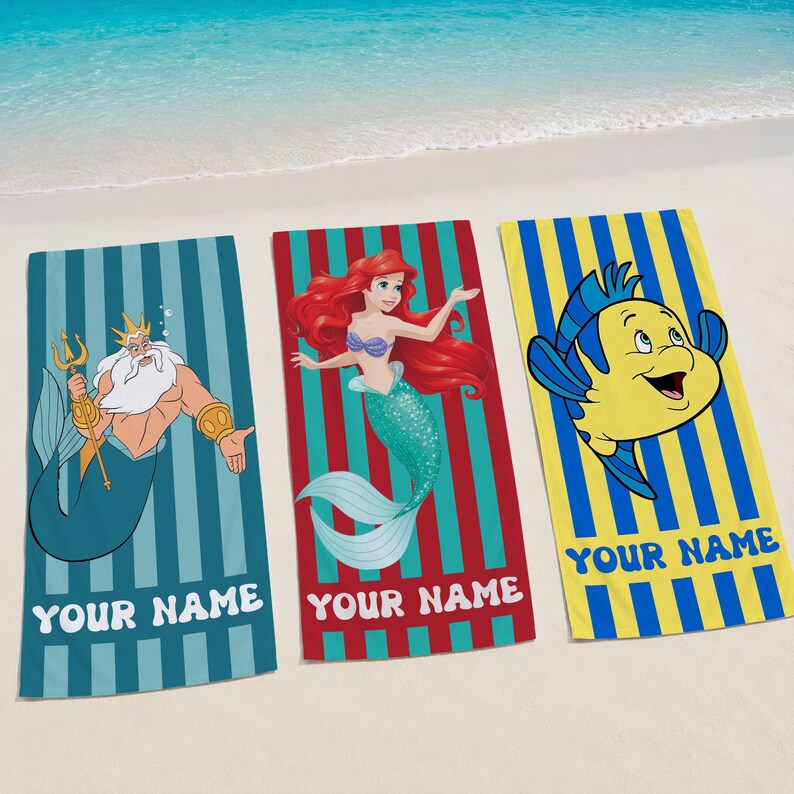 May include: Three beach towels with cartoon characters and the text "YOUR NAME". One towel features a teal background with a cartoon of King Triton. Another has a red background with Ariel. The third has a yellow background with Flounder.