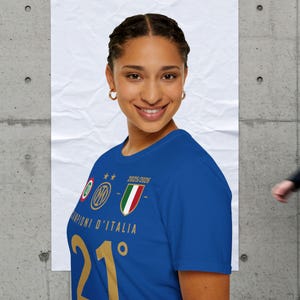 Könnte beinhalten: Ein blaues T-Shirt mit goldenem Text und italienischen Teamemblemen. Das Shirt trägt die Worte "Campioni d'Italia" und die Nummer "21". Das Shirt hat auch den Text "2025/2026".