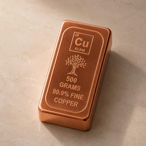 Op de afbeelding: Een rechthoekige koperen baar met een geborstelde afwerking. De bovenzijde bevat het periodiek symbool voor koper Cu 63.546, een boomillustratie en de tekst 500 GRAMS 99.9% FINE COPPER. De baar heeft afgeronde randen.