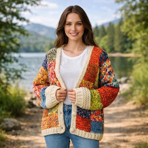 Könnte beinhalten: Eine grob gestrickte Strickjacke mit einem mehrfarbigen Patchwork-Design aus roten, orangen, gelben, grünen und blauen Garnblöcken. Das Kleidungsstück hat einen cremefarbenen Rippsaum an der Vorderöffnung, den Ärmelbündchen und am Saum mit Knöpfen.