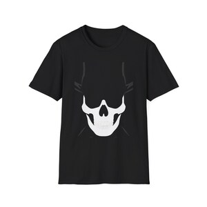Può includere: T-shirt nero con un disegno di teschio bianco. Il teschio ha un aspetto stilizzato con una mascella e orbite prominenti. Il disegno è centrato sulla maglietta, creando un'affermazione grafica audace. La maglietta è realizzata in materiale morbido.