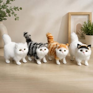 Peut inclure: Quatre figurines de chat en peluche alignées. La première est entièrement blanche, la deuxième présente des rayures grises et noires, la troisième est rayée orange et blanche, et la quatrième est blanche avec des taches noires et orange sur la tête.
