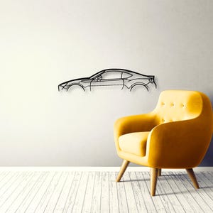 以下が含まれることがあります： スポーツカーのシルエットをミニマルな輪郭で表現した黒い金属製のウォールアート。ルーフライン、窓、ホイールアーチなど、車両の側面プロファイルを捉えたデザインで、壁面に直接取り付けられています。