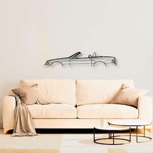 May include: A black metal wall art piece featuring the minimalist outline of a convertible car. The design captures the side profile of the vehicle, including the hood, windshield, open cabin area, and rear trunk section in a single continuous line.