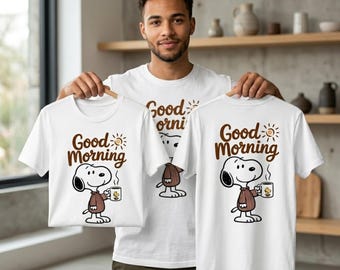 Könnte beinhalten: Weiße T-Shirts mit Snoopy, der eine Kaffeetasse hält, und dem Schriftzug "Good Morning" in Braun. Die Shirts sind kurzärmelig und haben ein Cartoon-Design. Das Bild zeigt drei Shirts, von denen eines getragen wird.