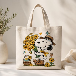 May include: Cream tote bag with a cartoon Snoopy character holding yellow flowers. Snoopy is wearing a brown hat, boots, and a yellow scarf. A small basket with the word "PEANUTS" is also visible.
