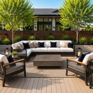 Puede incluir: Juego de muebles de patio al aire libre con un gran sofá seccional blanco, dos sillones y una mesa de centro cuadrada. El juego incluye cojines azul marino y estampados. El escenario es en una terraza de madera con árboles y una valla de madera al fondo.