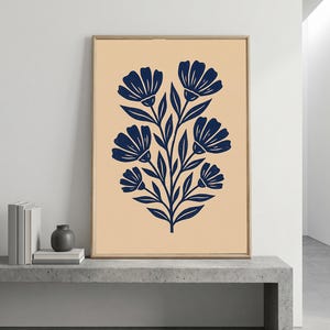 May include: A rectangular wall art print in a light wooden frame featuring a dark navy blue botanical illustration of a central stem with six stylized flowers and leaves against a solid, muted beige background.