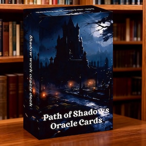 May include: A dark blue oracle card deck box with the title "Path of Shadows Oracle Cards" in white text. The box features a nighttime landscape with a castle, a full moon, and a path. The words "Shadow work oracle deck" are printed vertically on the side.