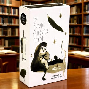 Puede incluir: Una caja de tarot blanca con el título "THE FUTURE ANCESTOR TAROT" en letras negras. La caja presenta ilustraciones de una mujer, hojas y gotas de agua. También están presentes las palabras "art & words by lexa luna studio".