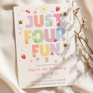 May include: A rectangular birthday invitation card with a cream background featuring the colourful text JUST FOUR FUN. The design includes illustrations of strawberries, bees, flowers, and a sun. Text details include Sofia's 4th Birthday, Saturday June 15th at 1PM, 1234 Two Fun Street, Suburb, and RSVP to Mum on 0412 123 123.