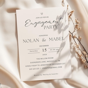Könnte beinhalten: Cremefarbene Einladungskarte zur Verlobungsfeier mit eleganten Schriftarten. Die Einladung enthält den Text „Feiern Sie mit uns die Verlobung“ und Details zur Feier von Nolan & Mabel am 15. Dezember um 17:00 Uhr.