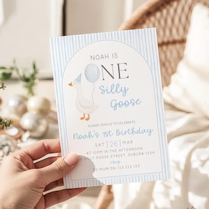 May include: A rectangular birthday invitation card featuring a light blue vertical striped border and an arched frame. The text reads: NOAH IS ONE silly Goose, PLEASE JOIN US TO CELEBRATE Noah's 1st Birthday, SAT 26 MAR, AT 12PM IN THE AFTERNOON, 13 SILLY GOOSE STREET, SUBURB 1234, rsvp TO MUM ON 123 123 123. A white goose wearing a blue party hat and holding a light blue balloon is illustrated on the left side.