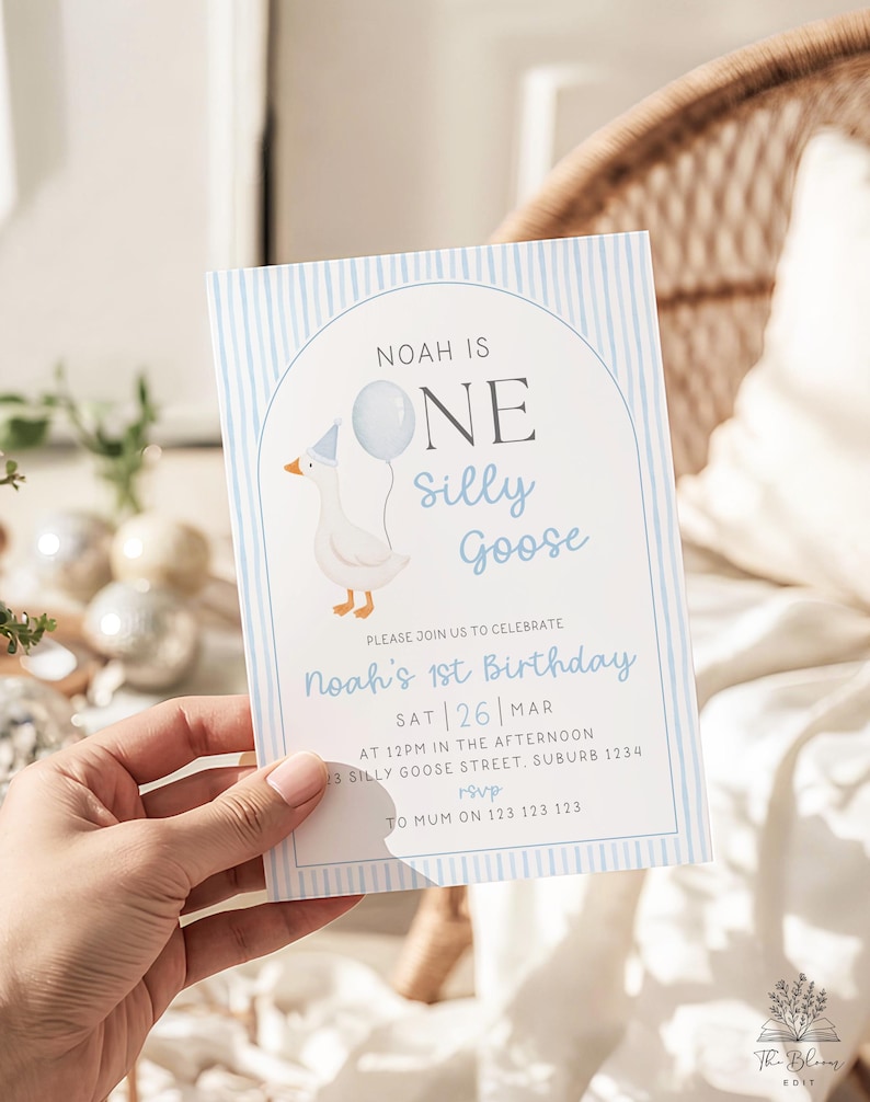 May include: A rectangular birthday invitation card featuring a light blue vertical striped border and an arched frame. The text reads: NOAH IS ONE silly Goose, PLEASE JOIN US TO CELEBRATE Noah's 1st Birthday, SAT 26 MAR, AT 12PM IN THE AFTERNOON, 13 SILLY GOOSE STREET, SUBURB 1234, rsvp TO MUM ON 123 123 123. A white goose wearing a blue party hat and holding a light blue balloon is illustrated on the left side.