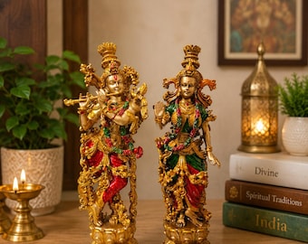 Puede incluir: Dos estatuas doradas ornamentadas de deidades sobre bases de loto. La figura de la izquierda toca una flauta y viste prendas rojas y verdes. La figura de la derecha tiene una mano levantada y viste un atuendo verde y rojo. Ambas tienen detalles intrincados.