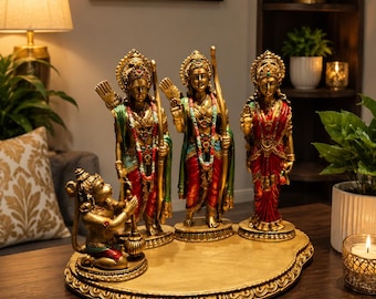 Puede incluir: Un conjunto de estatuas doradas con cuatro figuras sobre una base compartida. Tres figuras de pie llevan coronas ornamentadas, joyas y túnicas coloridas en rojo y verde. Una figura más pequeña se arrodilla al frente sosteniendo una maza.